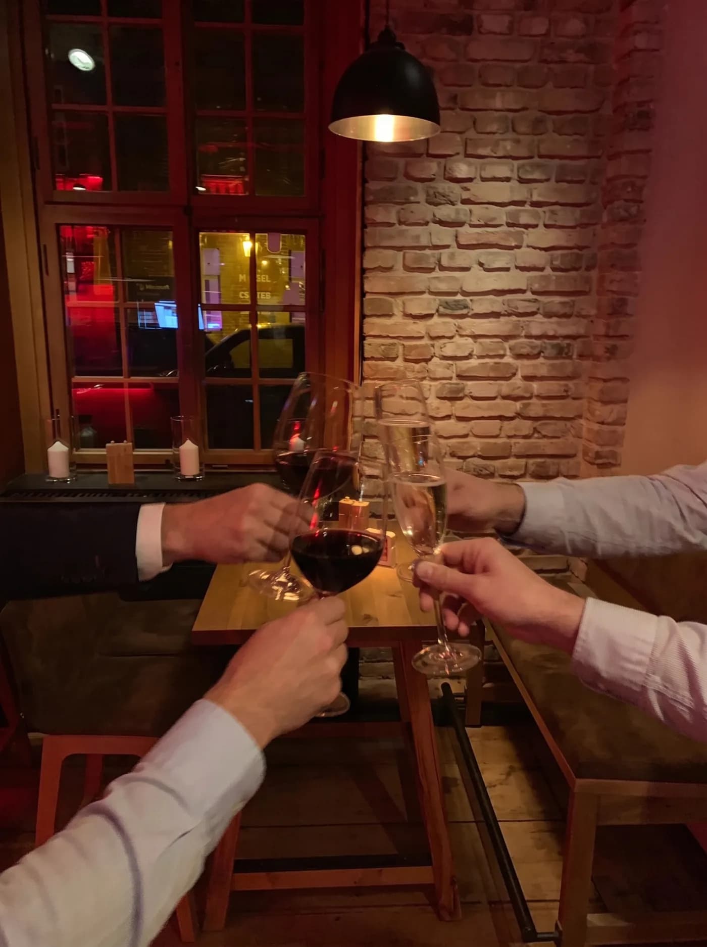 Anstoßen mit Wein und Sekt am Tisch vor der Ziegelwand