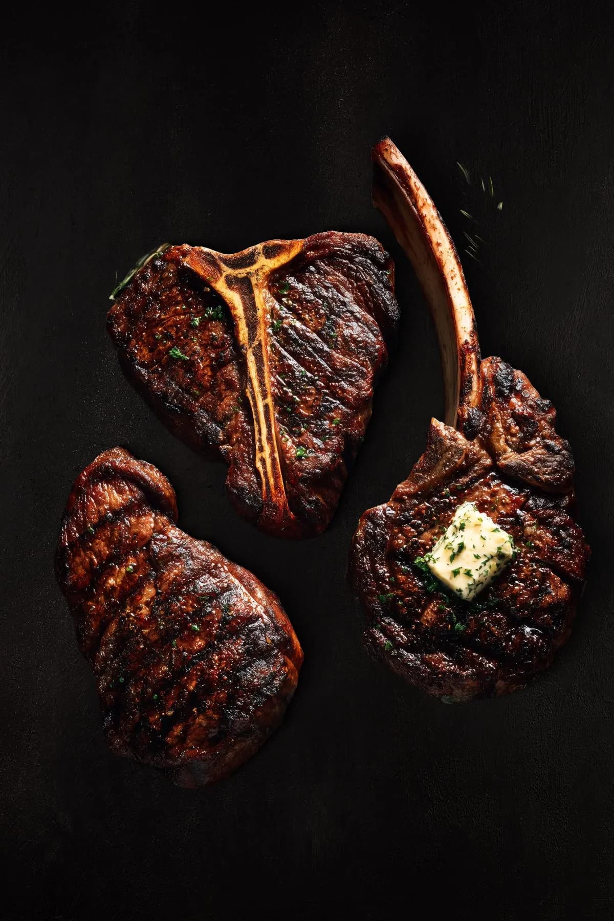 T-Bone, Tomahawk und Ribeye auf dunklem Grund
